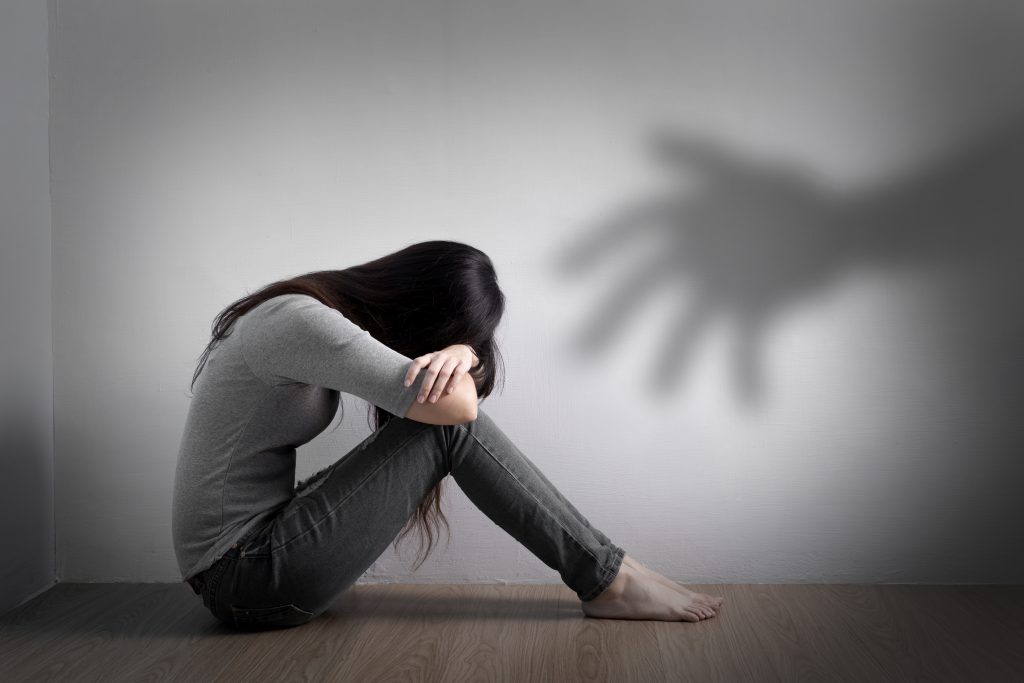 Shadow of a hand person sitting on floor head btw knees
