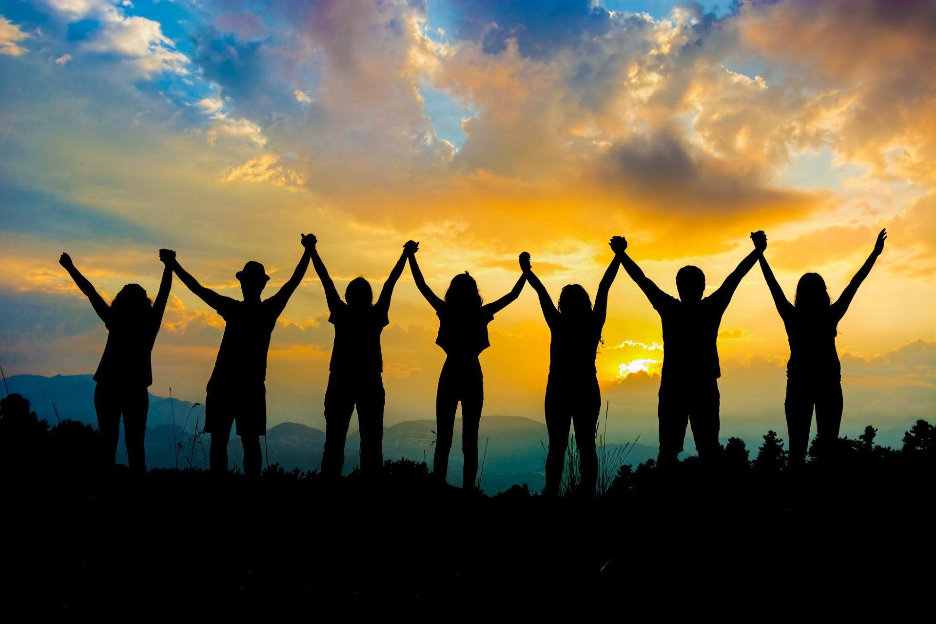 Grup of people standing ahead of sunset.