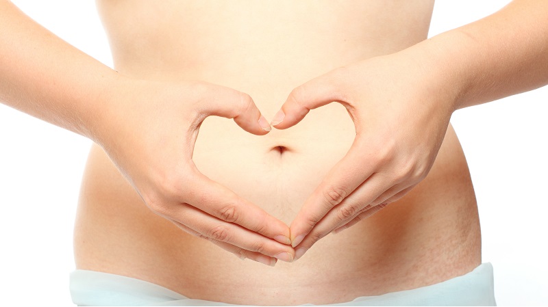 woman holding her hands in a shape of a heart in front of her stomach