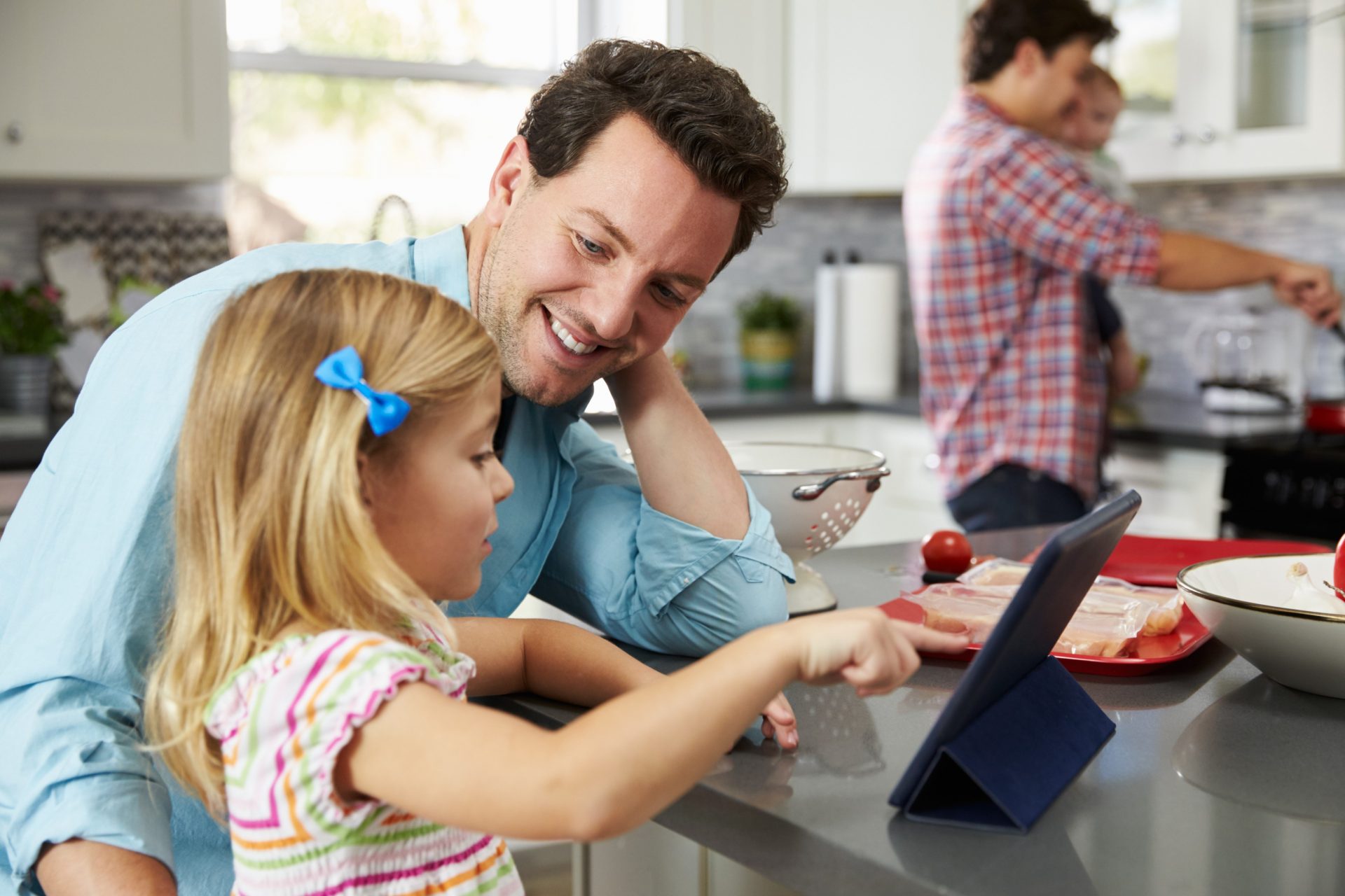 Samesex couple (male) with their kids in the kitchen.