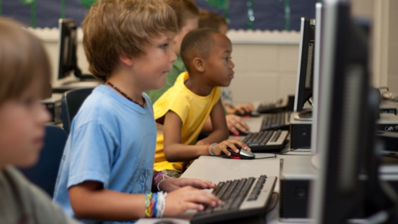 Pojat pelaavat koulun tietokoneluokassa koneilla.