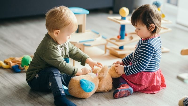 Kaksi pikkulasta leikkii lattialla.