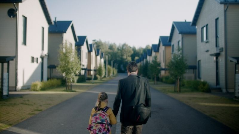 Father and daughter walking hand in hand outside not facing the camera.