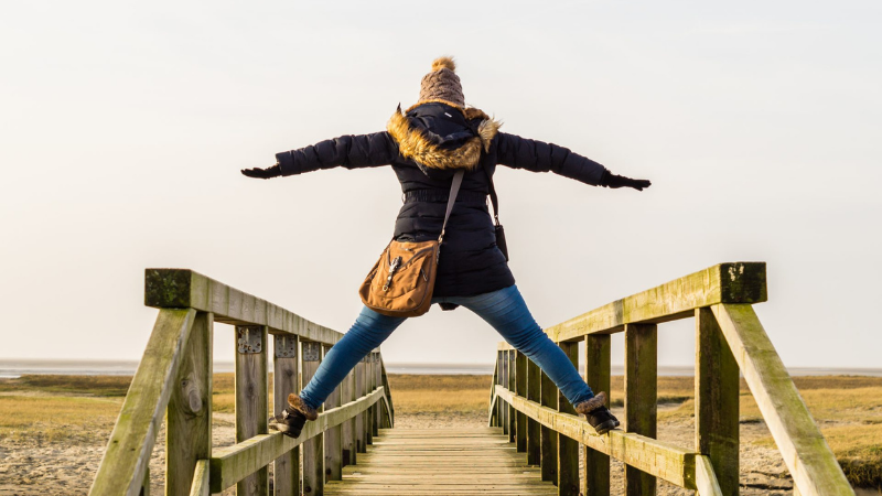 A person is balancing on a bridge in a pretty autumn scenery.