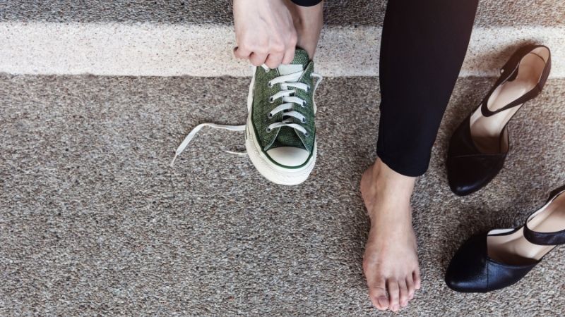 A Woman changing from working shoes to sneakers.