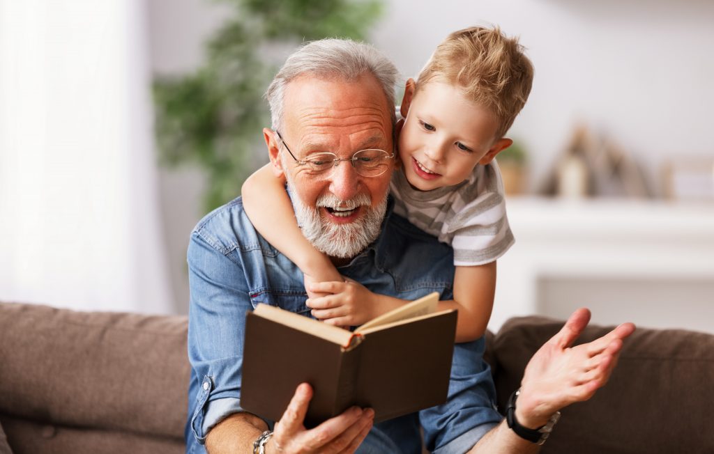 Isoisä ja ja lapsenlapsi lukevat yhdessä kirjaa.