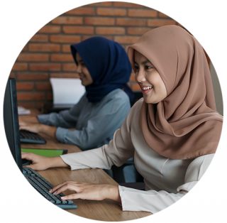 Kaksi huivipäistä nuorta naista työskentelevät tietokoneilla.