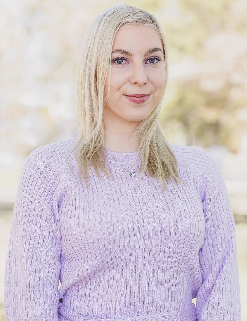 Vaaleat keskipitkät hiukset ja lila neule.