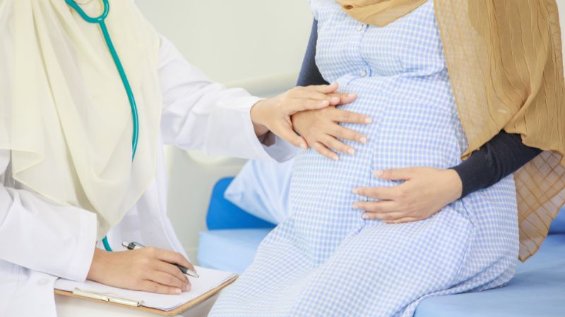 Lääkäri kuuntelee stetoskoopilla raskaana olevan naisen vatsaa.