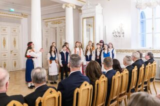 Tapiolan kuoron ryhmä esiintyy. Heillä on kansallispuvut.