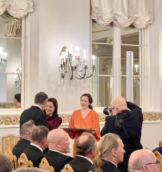 Väestöliiton puheenjohyaja Hilkka Kemppi avustaa ministeriä kunniamerkkien kiinnittämisessä.