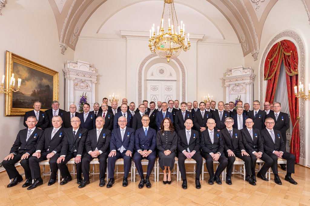 Kunniamerkin saaneiden isien ryhmäkuva, jossa keskellä istuu myös presidenttipari.